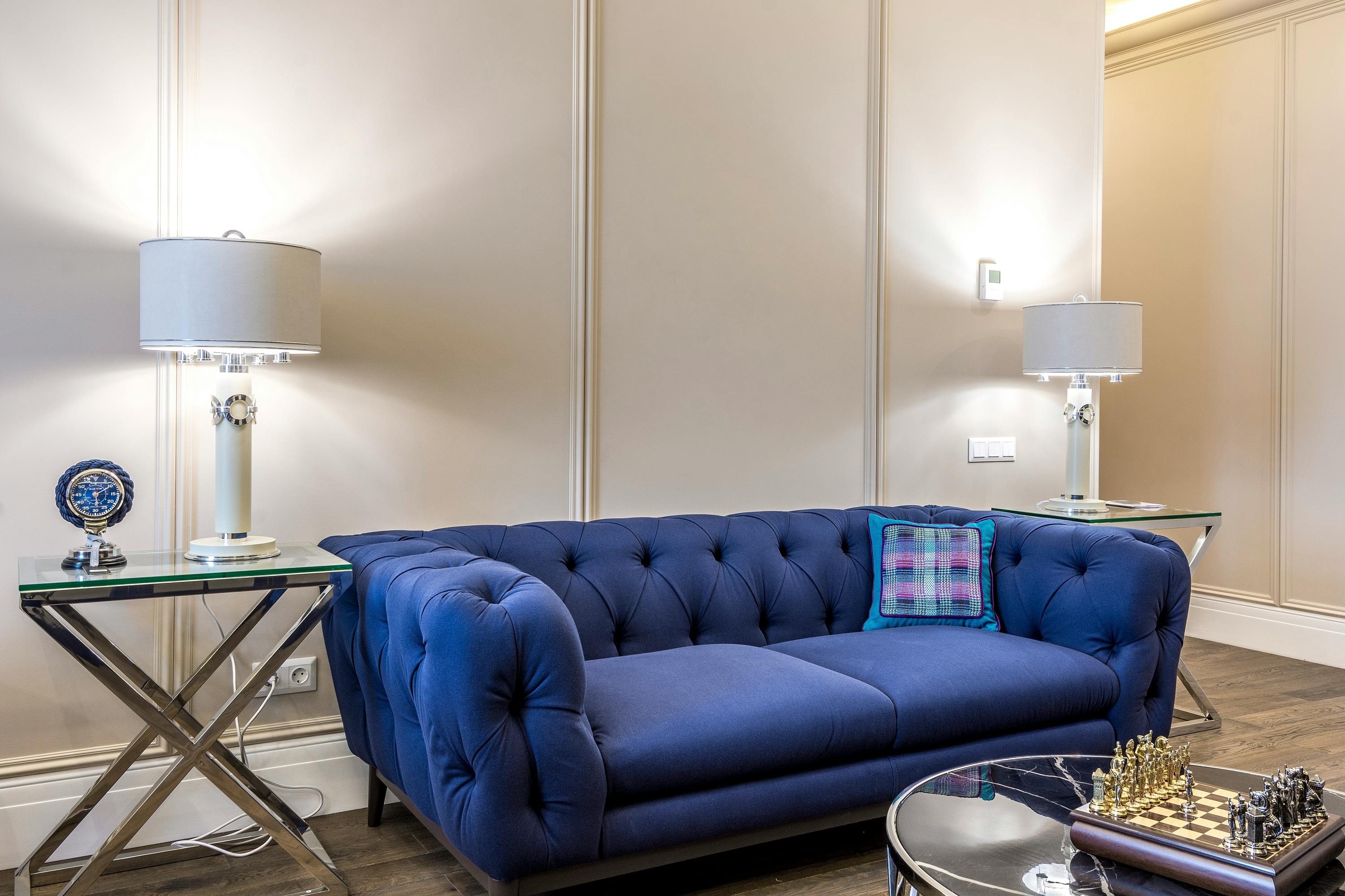 A blue couch positioned in a room with a table and lamps, enhancing the space's comfort and style